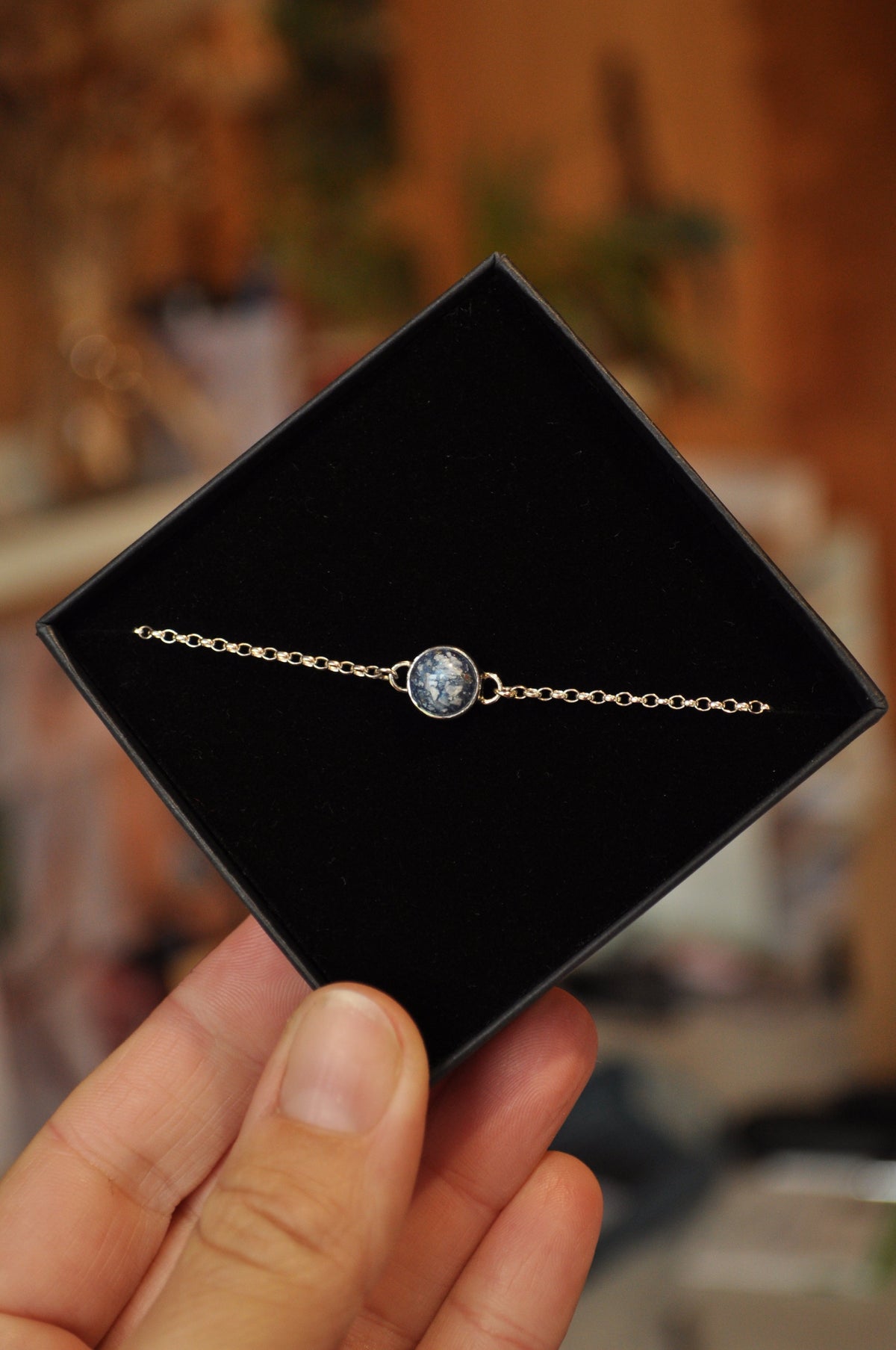 Fine gold memorial bracelet with a small round ashes inclusion, presented on a black velvet jewellery display box