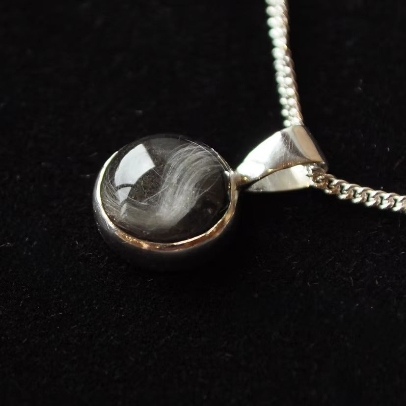 Silver dog fur necklace with a black stone pendant on a dark background