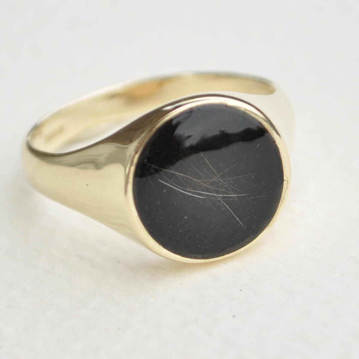 Gold signet ring with a black pet fur stone on a white background