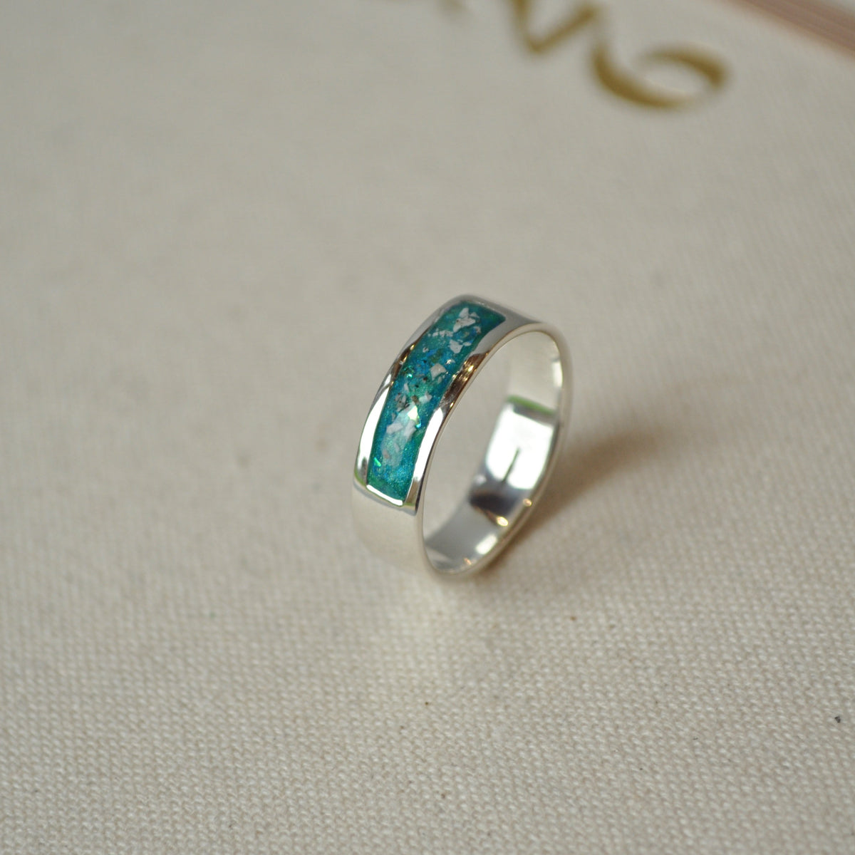 Silver ring with turquoise ashes stones on a beige fabric background