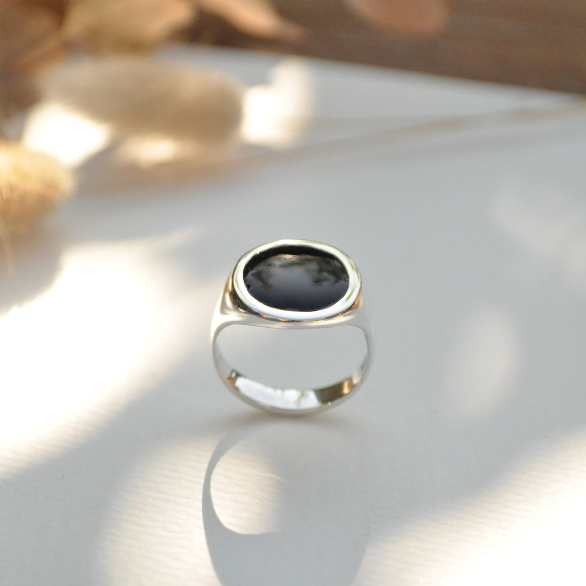Silver ring with a black stone on a white background