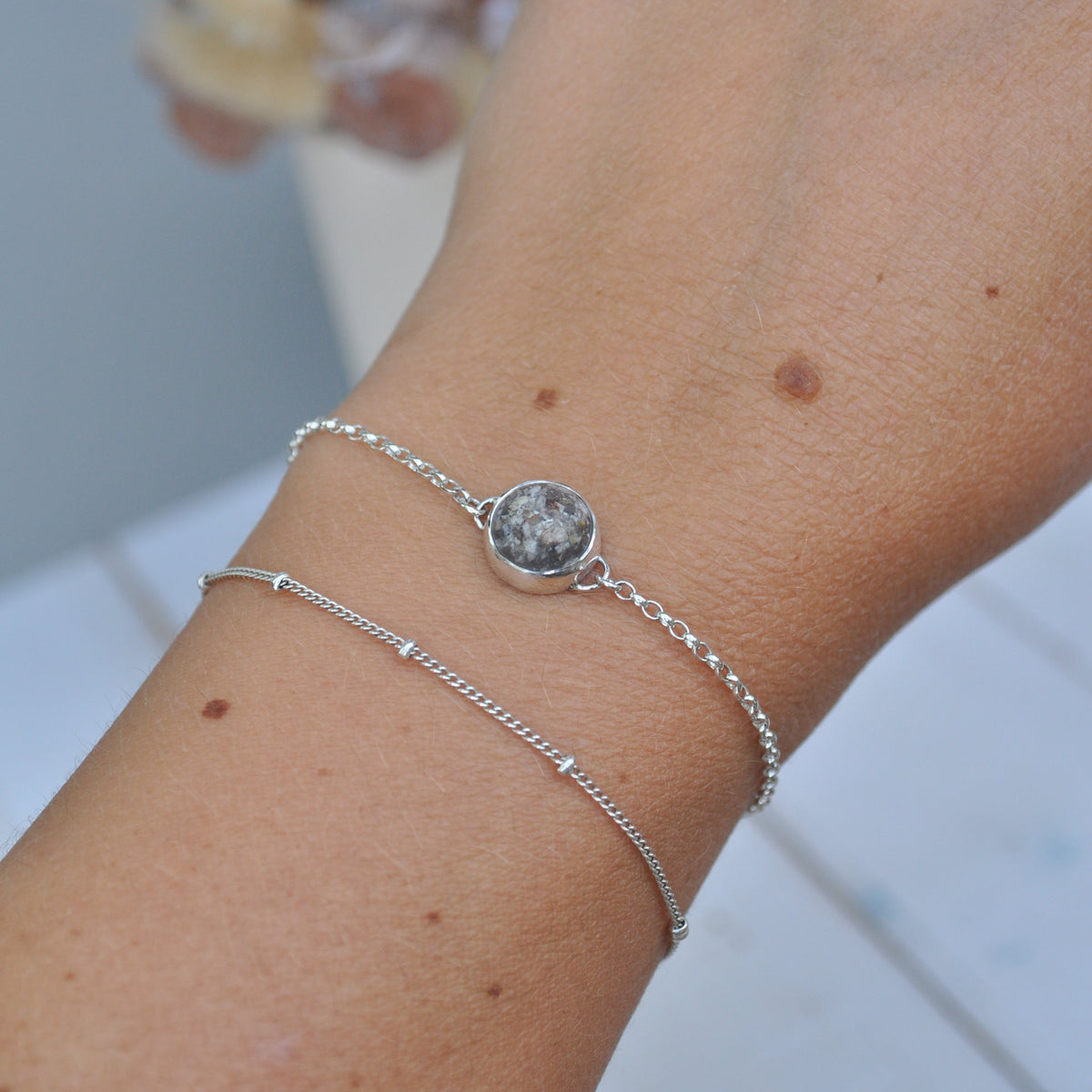 Silver bracelet with ashes on a wrist with a blurred background