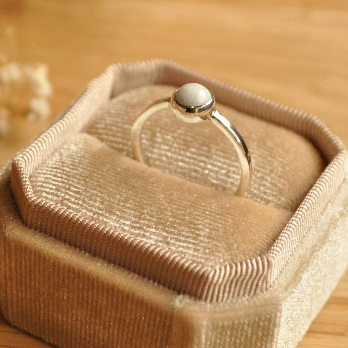 Beige jewellery box with a silver breastmilk ring on a wooden surface