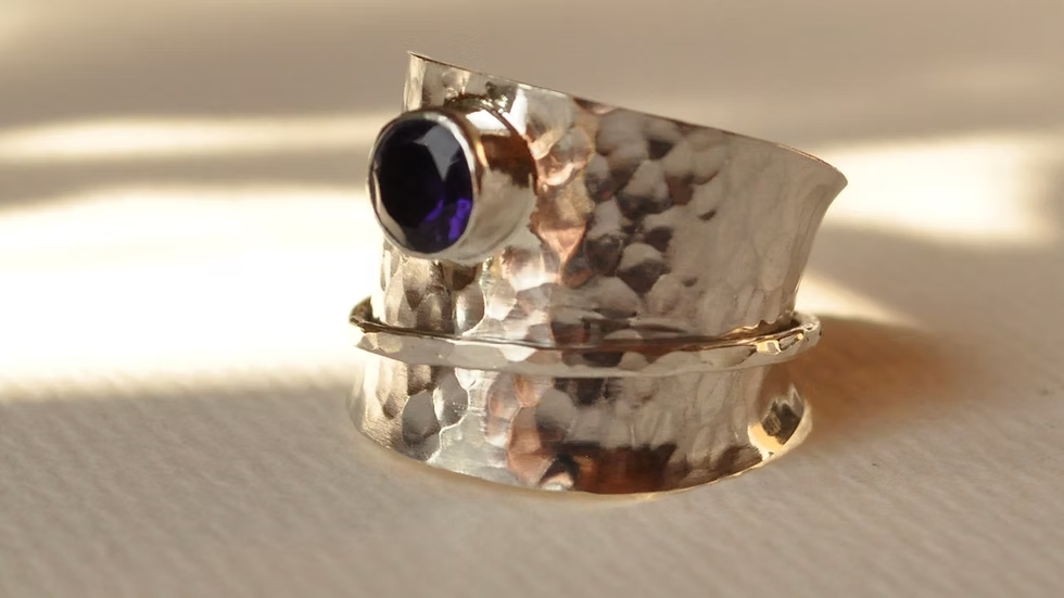 Silver ring with a purple gemstone on a light background