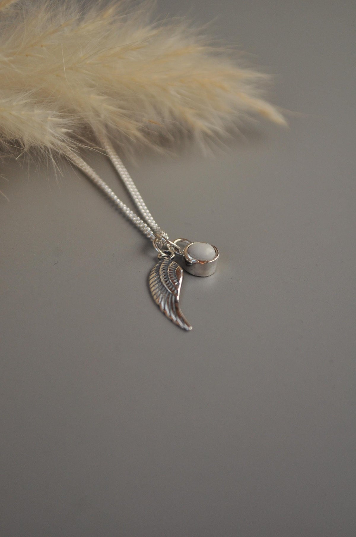 Angel wing breastmilk necklace on a neutral background | Mila Faith