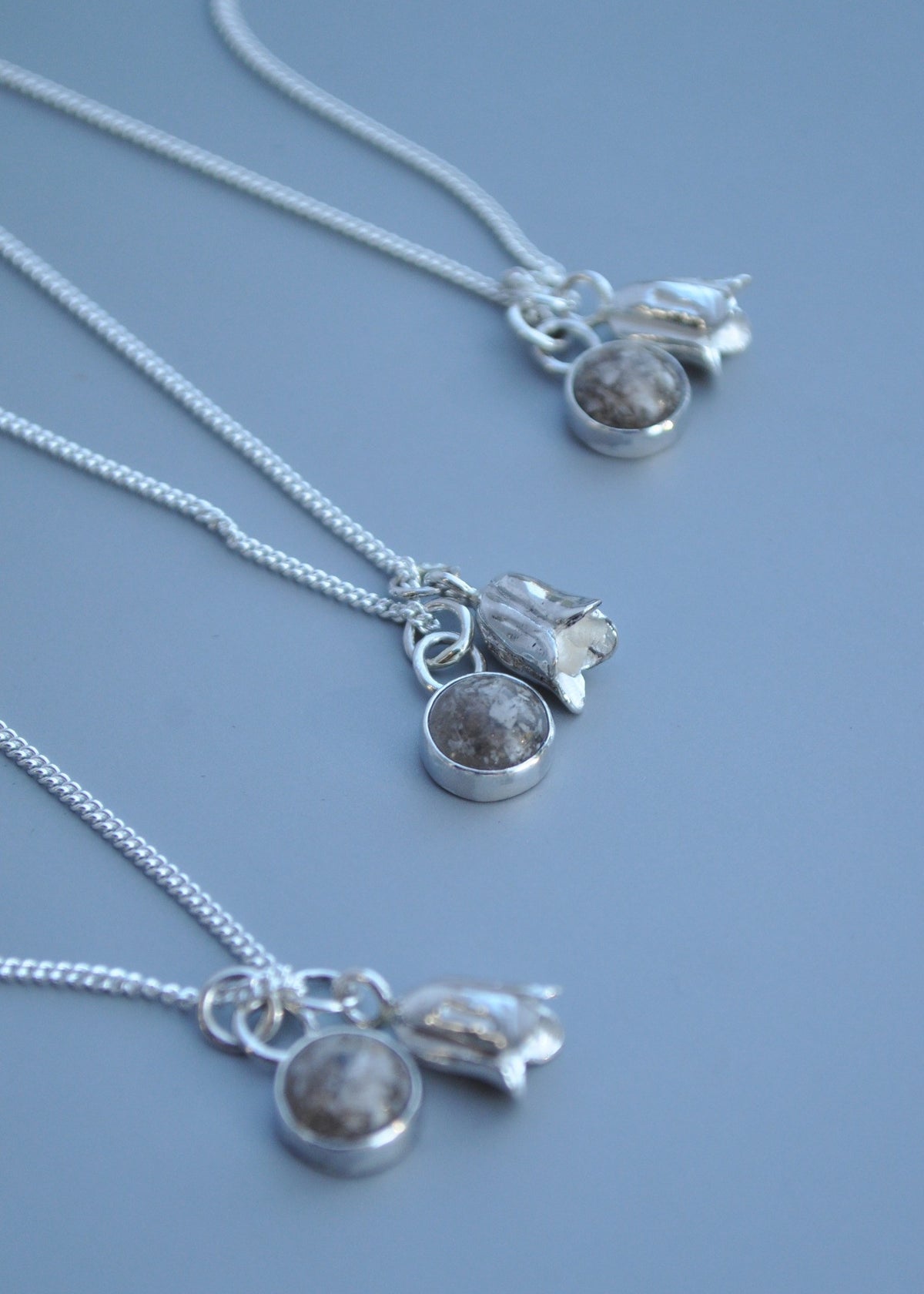 Mila Faith ashes pendant necklace with a bluebell charm, displayed on a blue background.