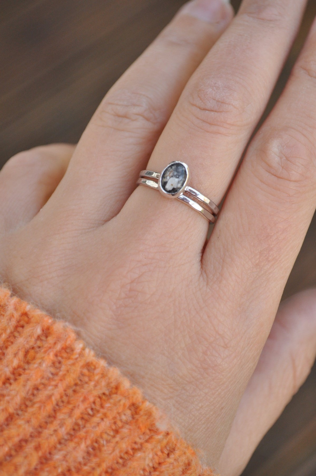Close-up of a silver ashes memorial ring and its stacking band.
