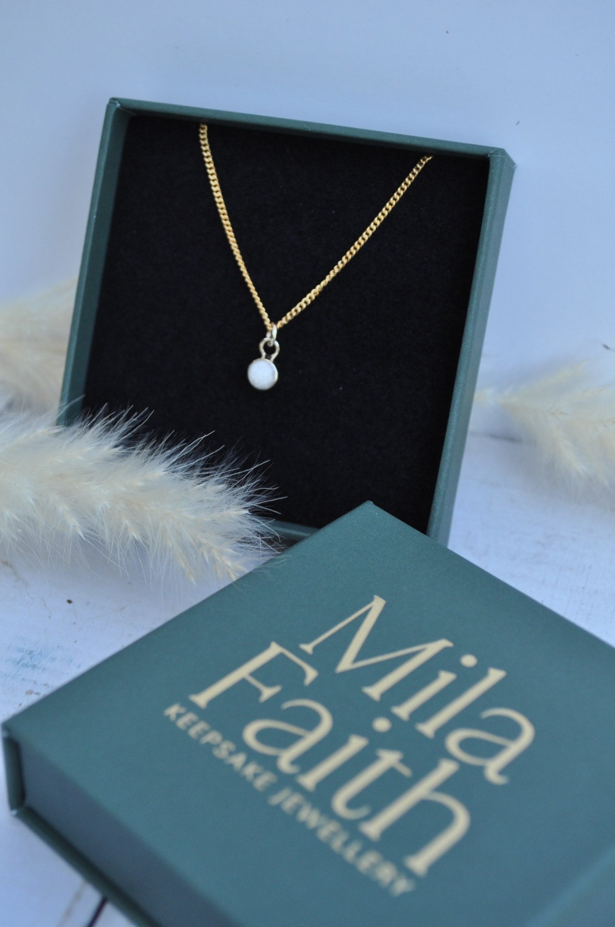 Mila Faith breastmilk pendant necklace with a gold-tone chain in its gift box.