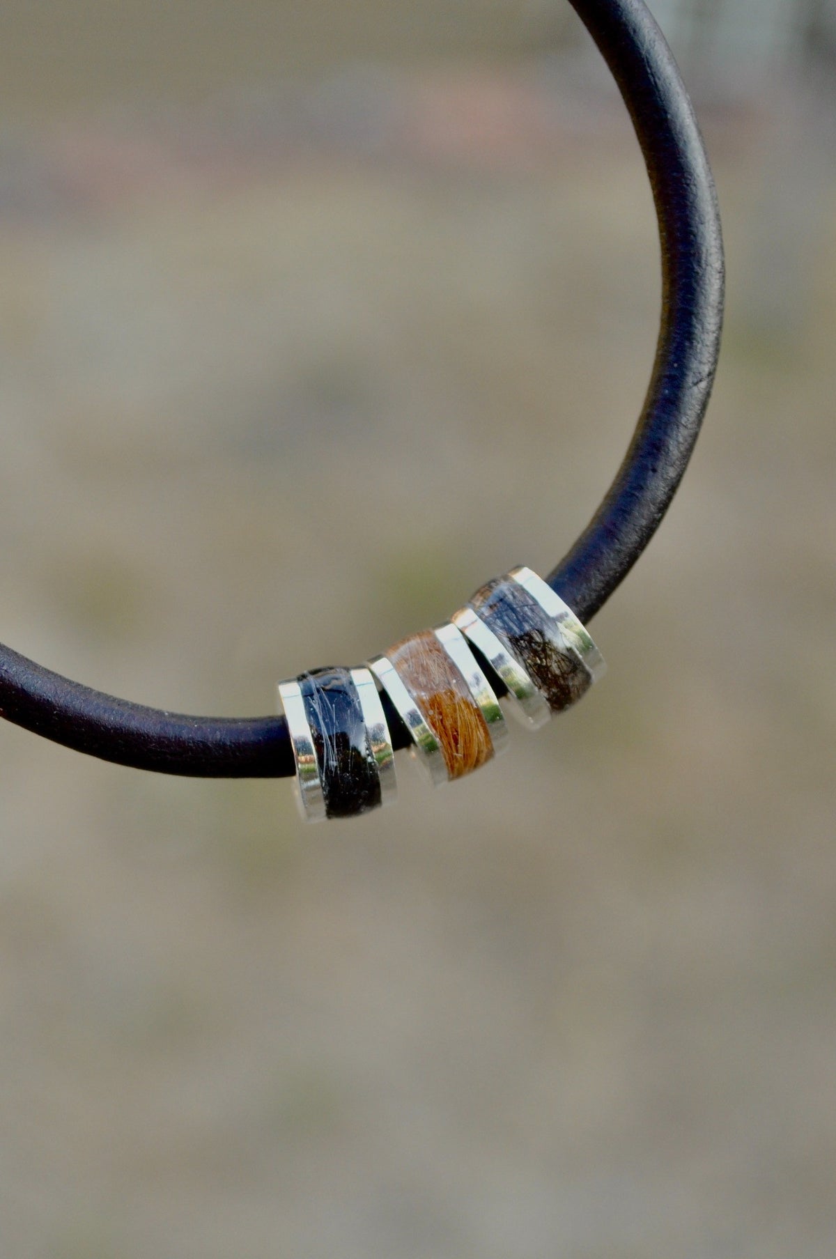 Close-up of a black leather cremation ashes memorial bracelet with a silver-tone bead.
