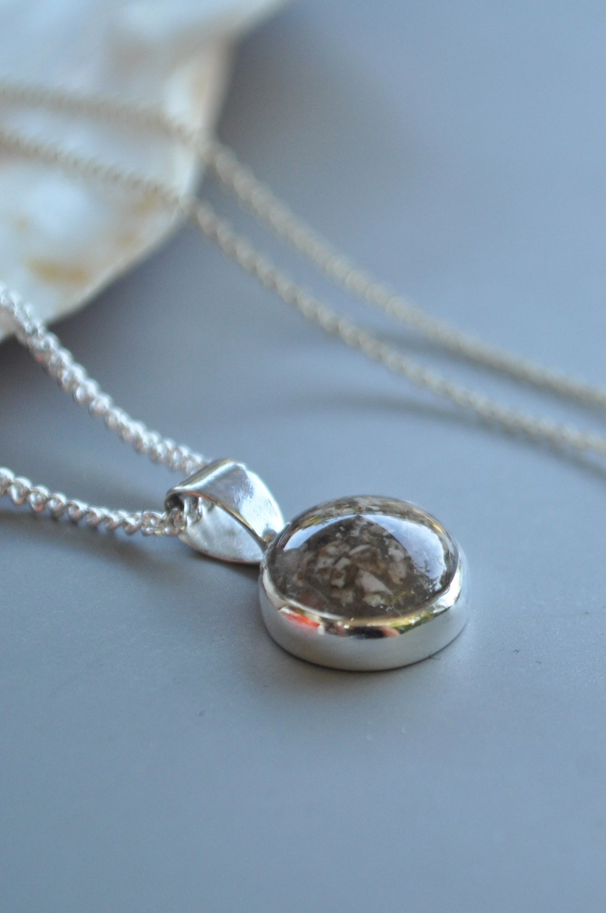 Silver cremation ashes pendant necklace with a round keepsake setting.